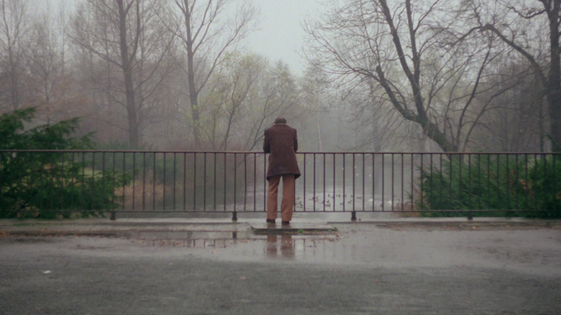 Im Still aus "Far From Home" wird von hinten gezeigt, wie ein Mann im Mantel an einem Brückengeländer steht und hinabschaut.