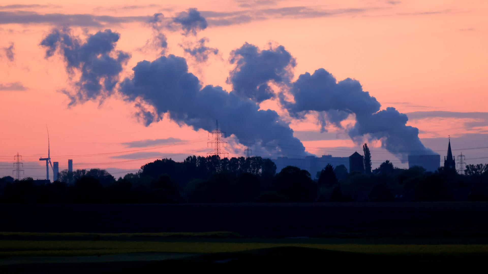 Dampfwolken steigen in der Dämmerung vom Kohlekraftwerk Niederaußem des Stromkonzerns RWE auf.