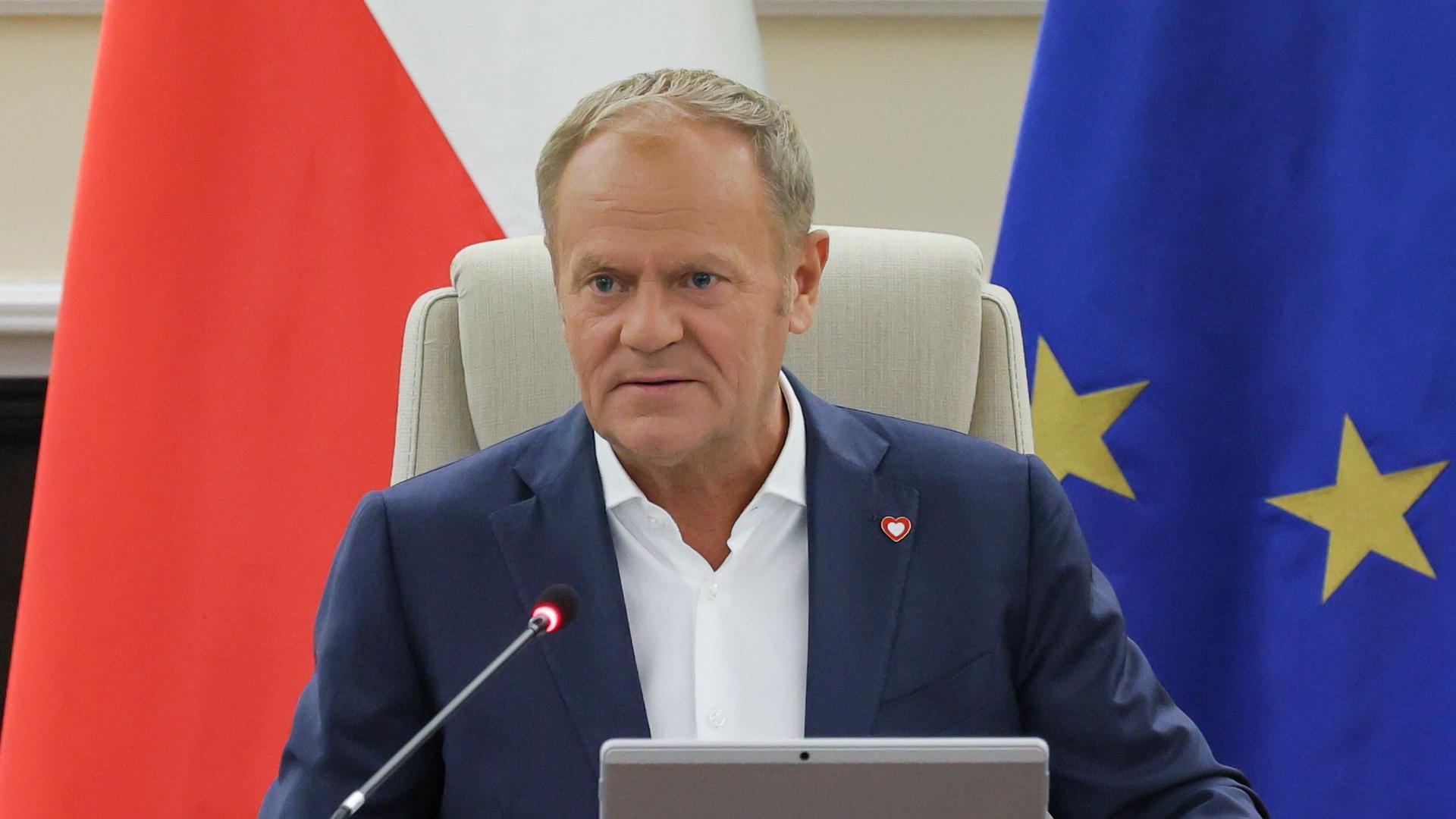 Der polnische Ministerpräsident Donald Tusk sitzt vor der polnischen Fahne und der EU-Flagge. Der polnische Ministerpräsident Donald Tusk sitzt vor der polnischen Fahne und der EU-Flagge.