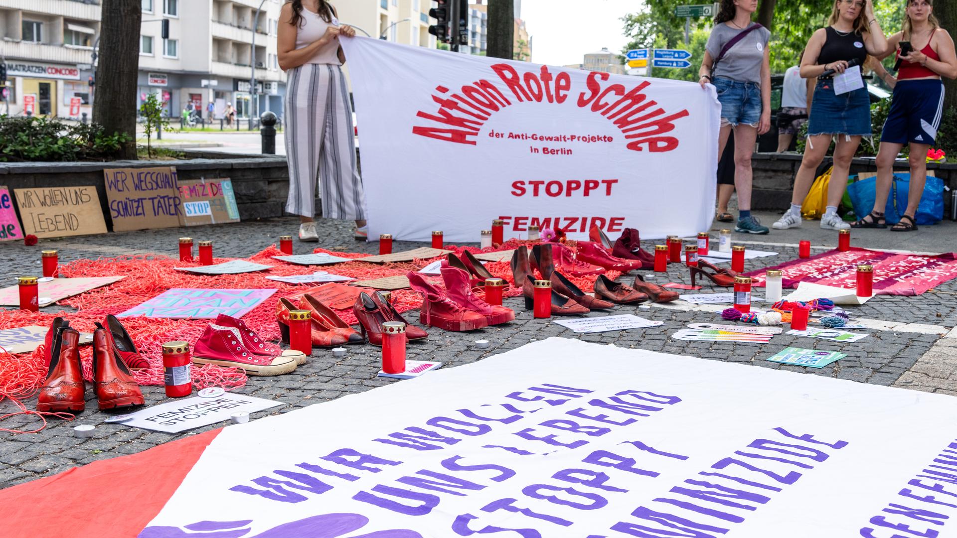 Teilnehmer der Kundgebung gegen Feminizide stehen in Schöneberg vor dem Rathaus Schöneberg und halten ein Transparent mit der Aufschrift "Aktion Rote Schuhe - Stoppt Femizide". Rote Schuhe gelten weltweit als Symbol für Gewalt an Frauen. Teilnehmer der Kundgebung gegen Feminizide stehen in Schöneberg vor dem Rathaus Schöneberg und halten ein Transparent mit der Aufschrift "Aktion Rote Schuhe - Stoppt Femizide". Rote Schuhe gelten weltweit als Symbol für Gewalt an Frauen.