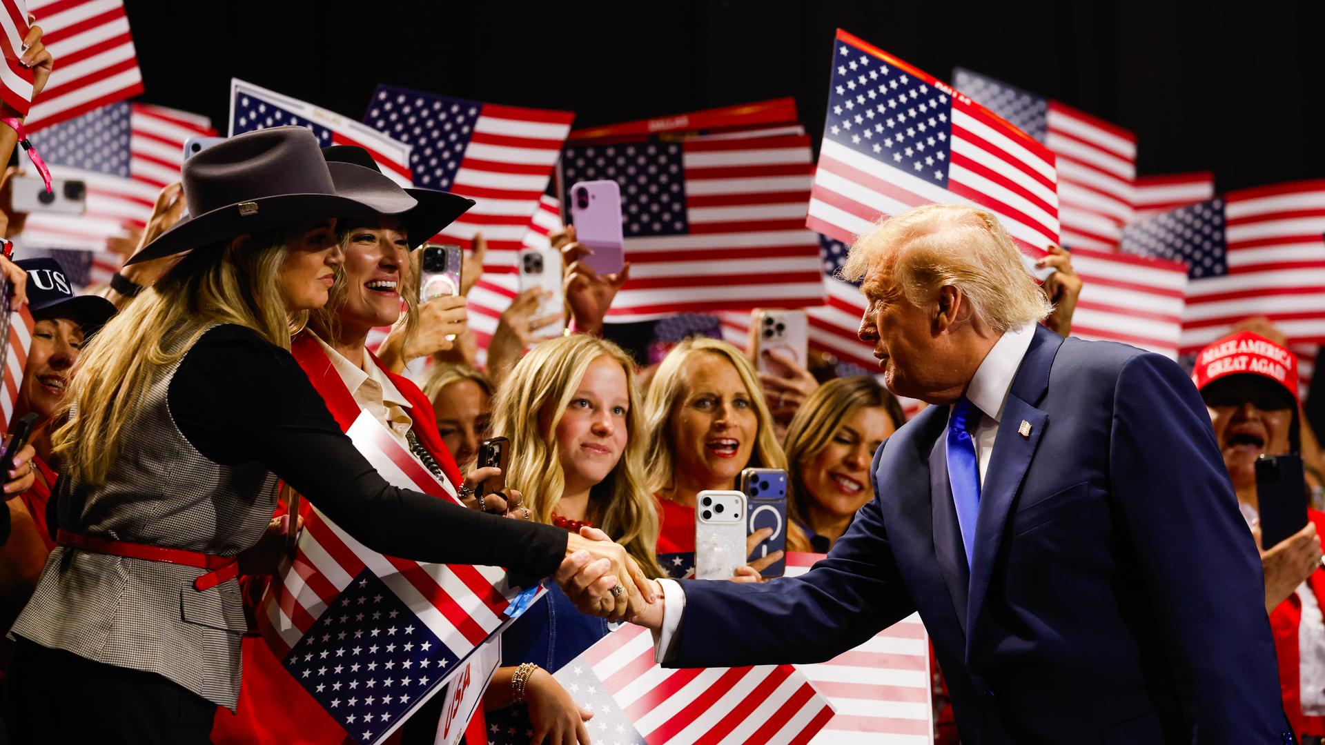 US-Präsident Donald Trump begrüßt Frauen mit Cowboy-Hüten in dem Bundes-Staat Texas. US-Präsident Donald Trump begrüßt Frauen mit Cowboy-Hüten in dem Bundes-Staat Texas.