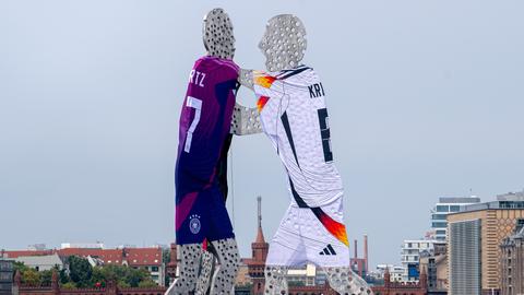 Die Statue Molecule Man in der Spree mit Trikots von Manuel Neuer, Florian Wirtz und Toni Kroos geschmückt