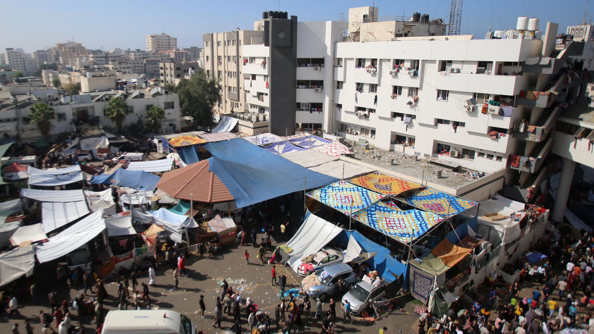 Das Gelände des Al-Shifa-Krankenhauses in Gaza-Stadt am 7. November 2023. Vor dem Gebäude sind mehrere Planen als Sonnenschutz angebracht, man sieht viele Menschen vor dem Krankenhaus.