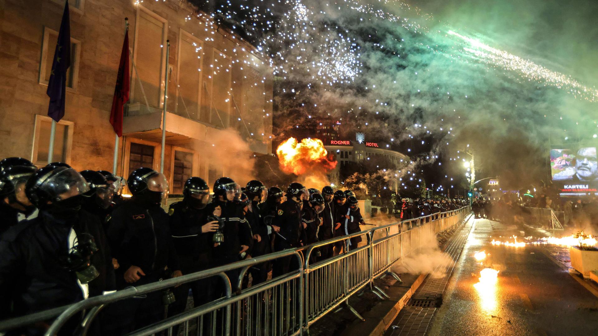 Vviele Polizisten stehen am Abend hinter Absperrgittern, mit denen sie Demonstranten fernhalten wollen. 