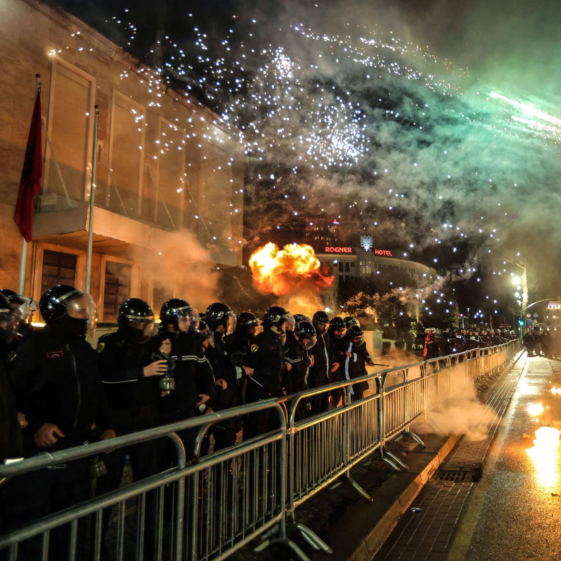 In Tirana stehen viele Polizisten am Abend hinter Absperrgittern, mit denen sie Demonstarnten fernhalten wollen. 