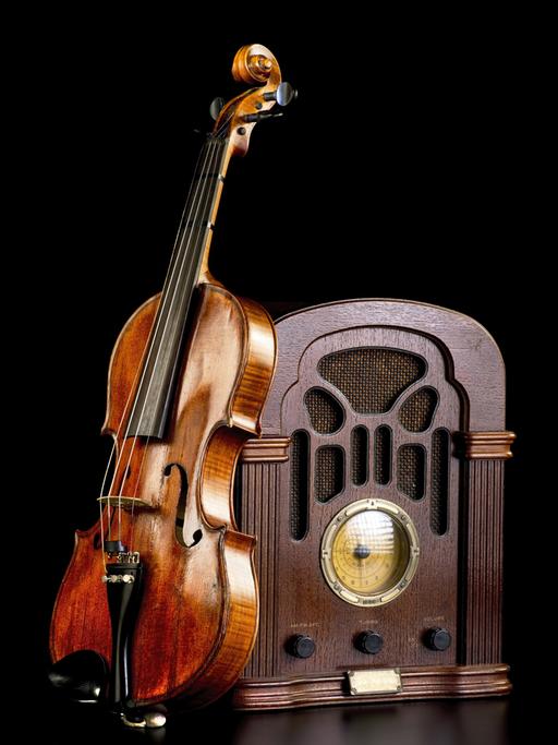 An einem historischen Radio lehnt eine Violine.