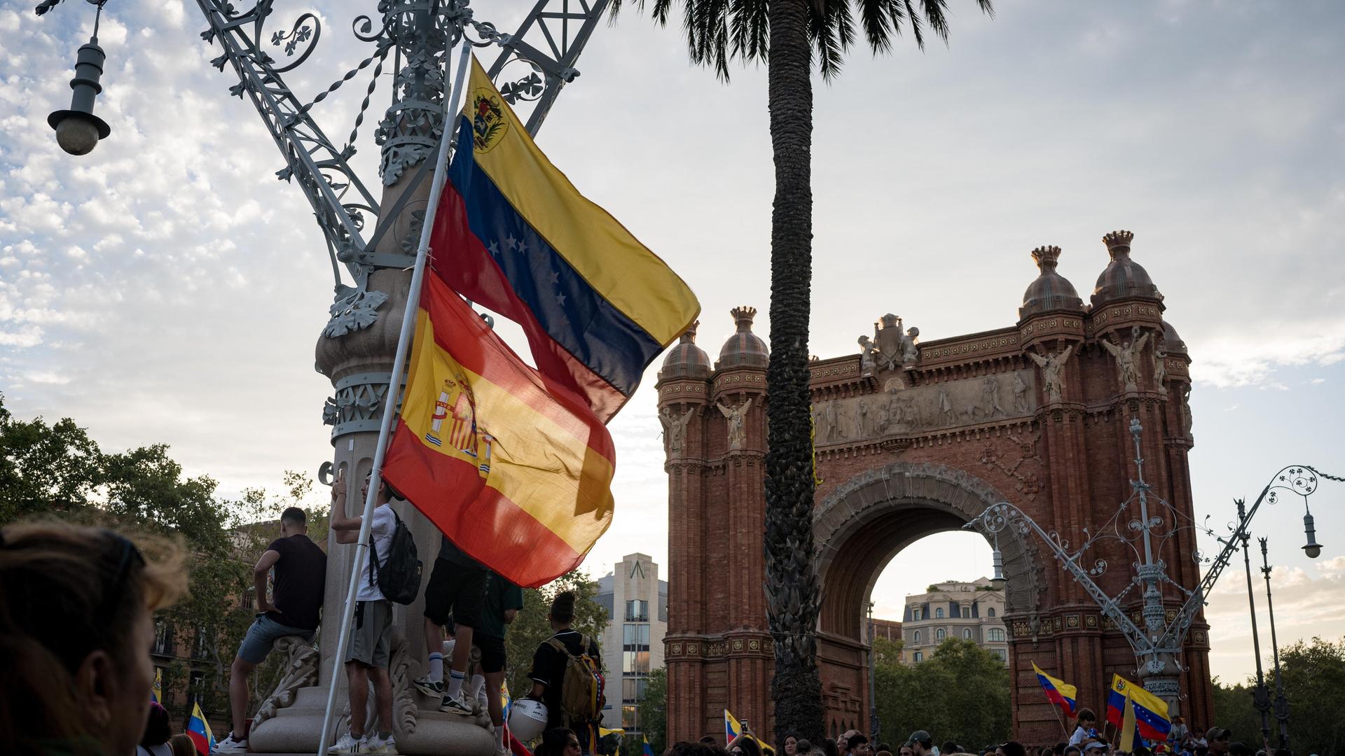 Die Flaggen Spaniens und Venezuelas sind bei einem Protest am Arc de Triomf in Barcelona zu sehen.