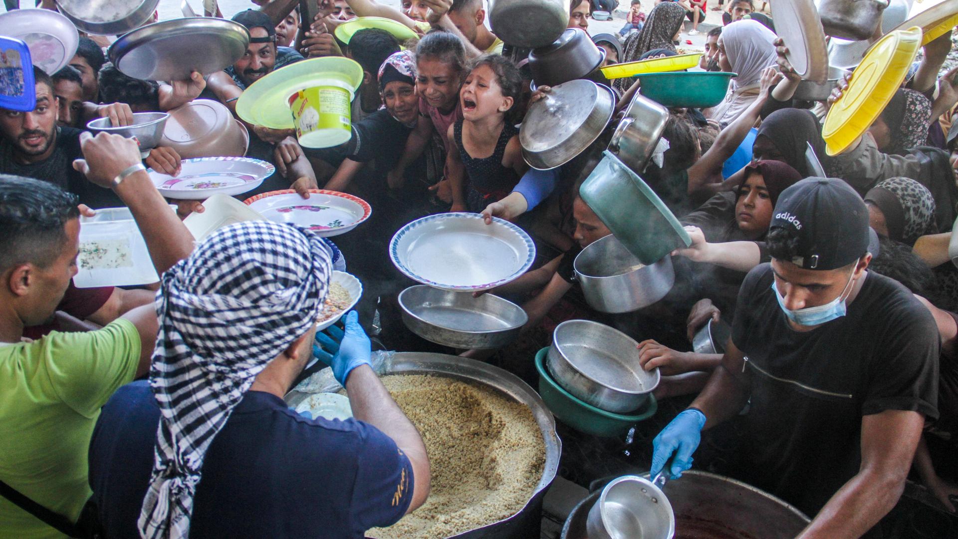 Palästinensische Kinder warten in der Stadt Beit Lahia im Gazastreifen mit ihren Gefäßen an einer Essensausgabe.