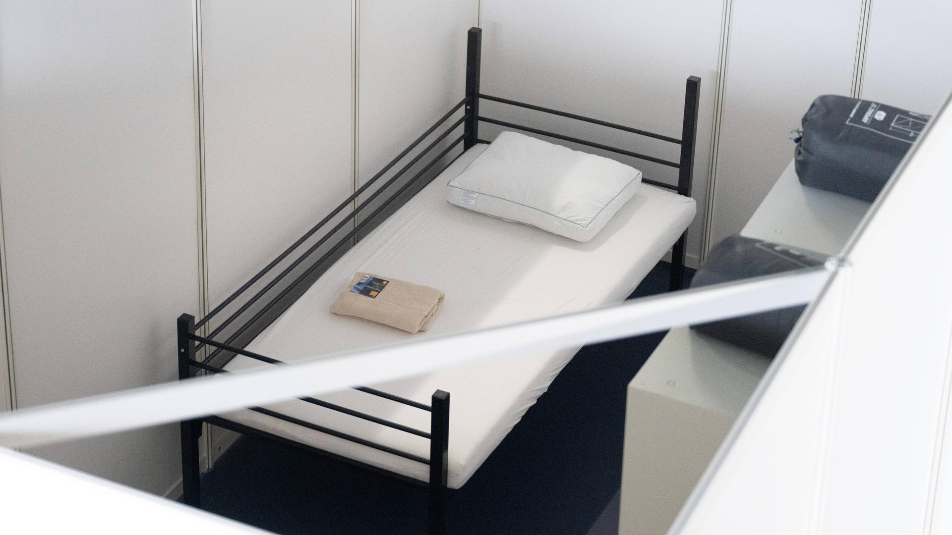 Ein Bett steht in einer Halle, die Flüchtlingsunterkunft werden sollte.