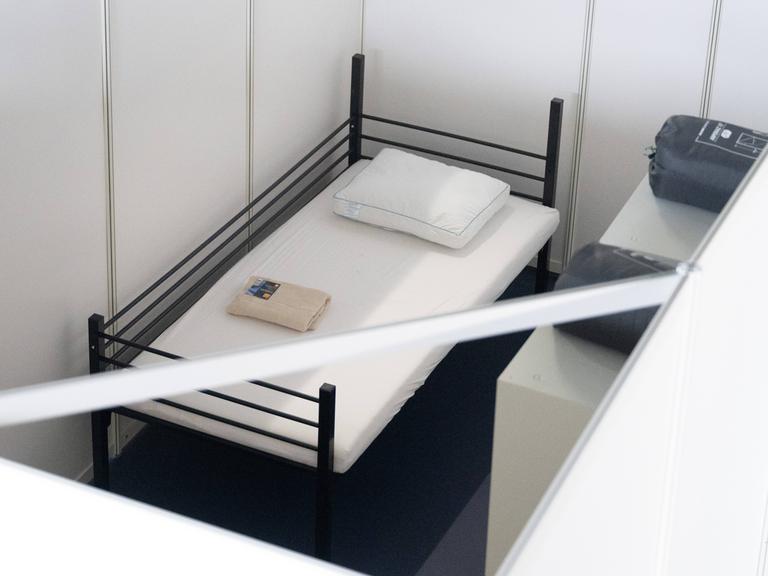 Ein Bett steht in einer Halle, die Flüchtlingsunterkunft werden sollte.