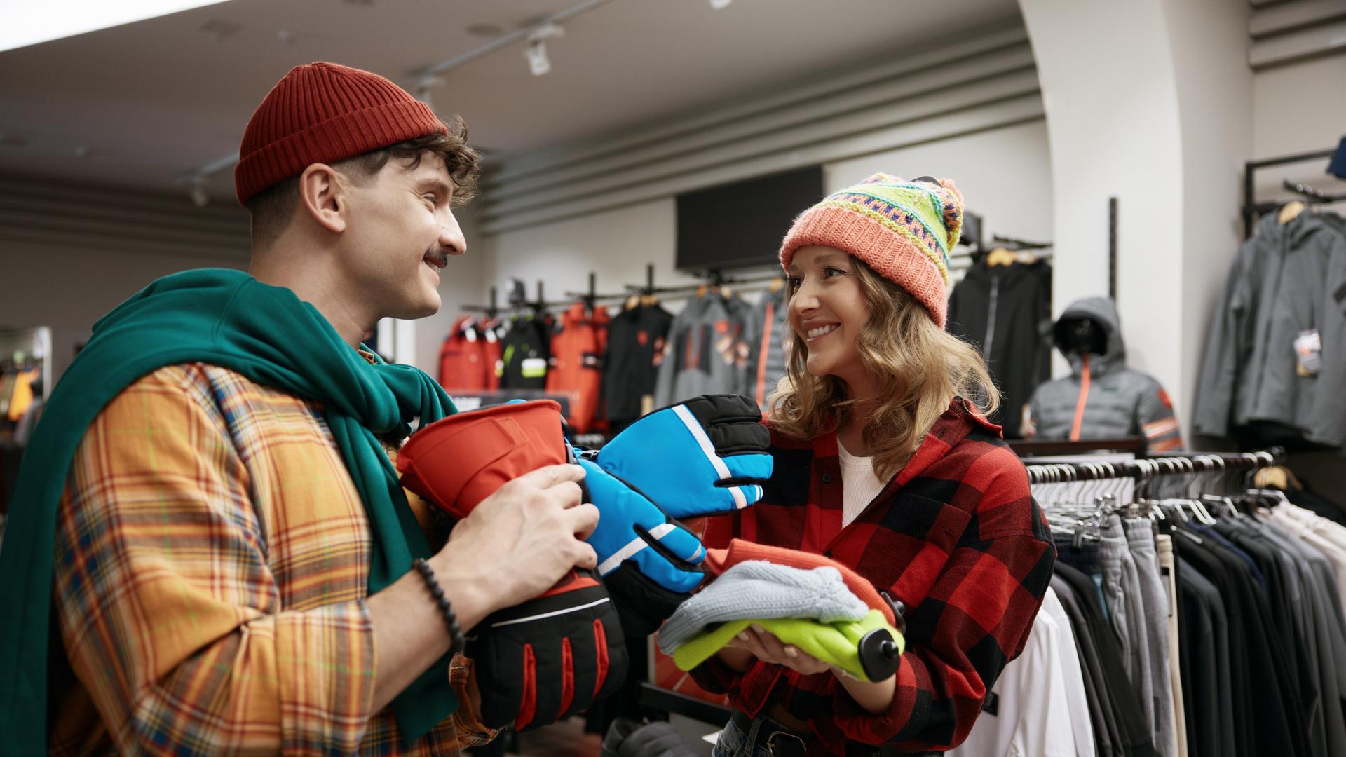 Junger Mann und junge Frau kaufen Sportausrüstung für eine Fahrradtour im Winter.