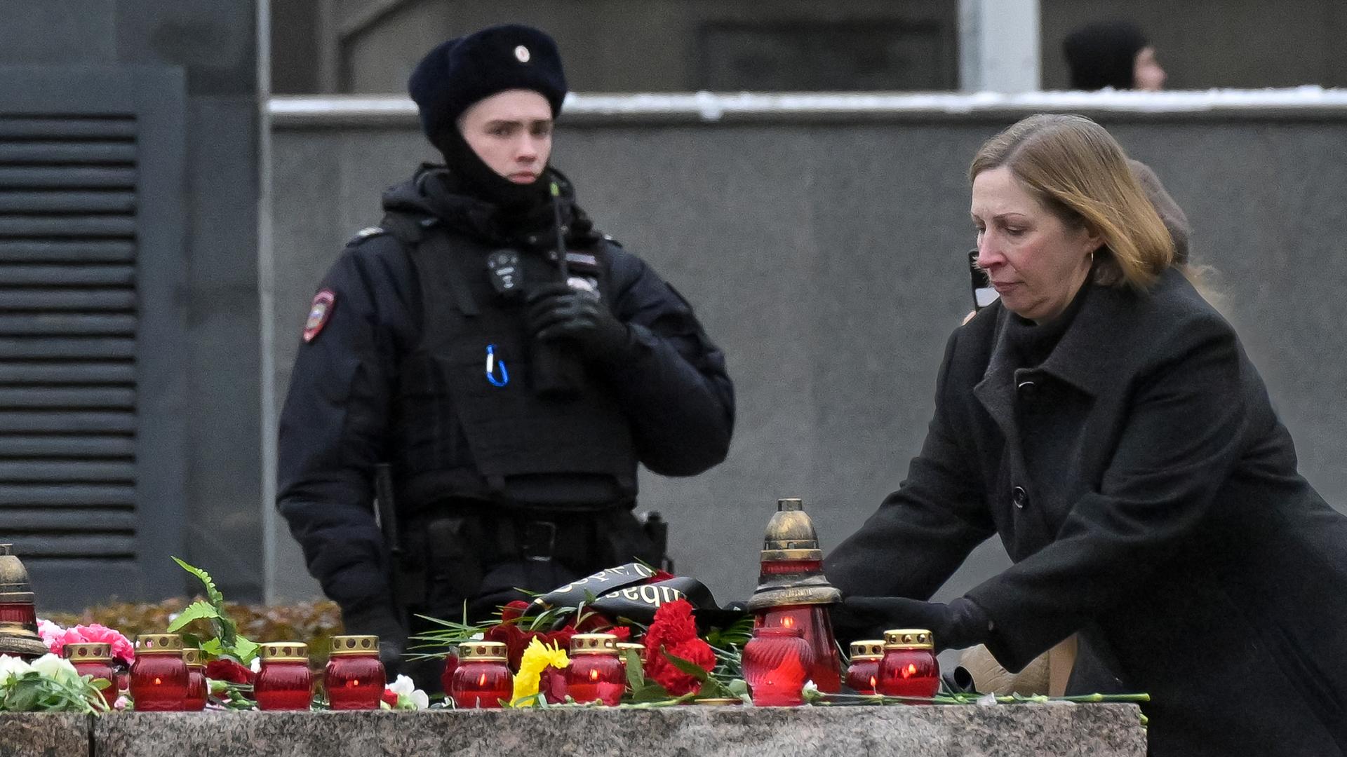 Gedenken an Stalin-Opfer in Russland: Ein Polizist bewacht einen Bereich, während Lynne Tracy, US-Botschafterin in Russland, Blumen niederlegt.