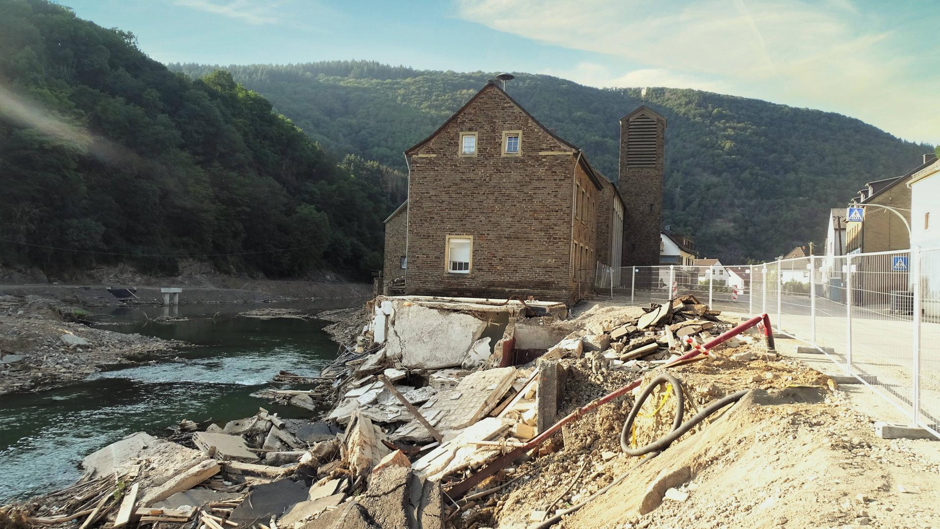 Ein Haus steht inmitten zerstörter Fundamente direkt am Fluss.