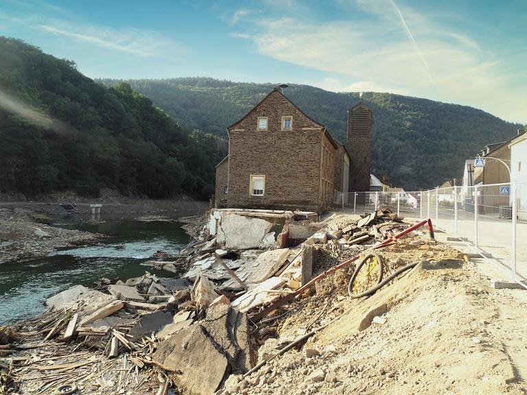Ein Haus steht inmitten zerstörter Fundamente direkt am Fluss.