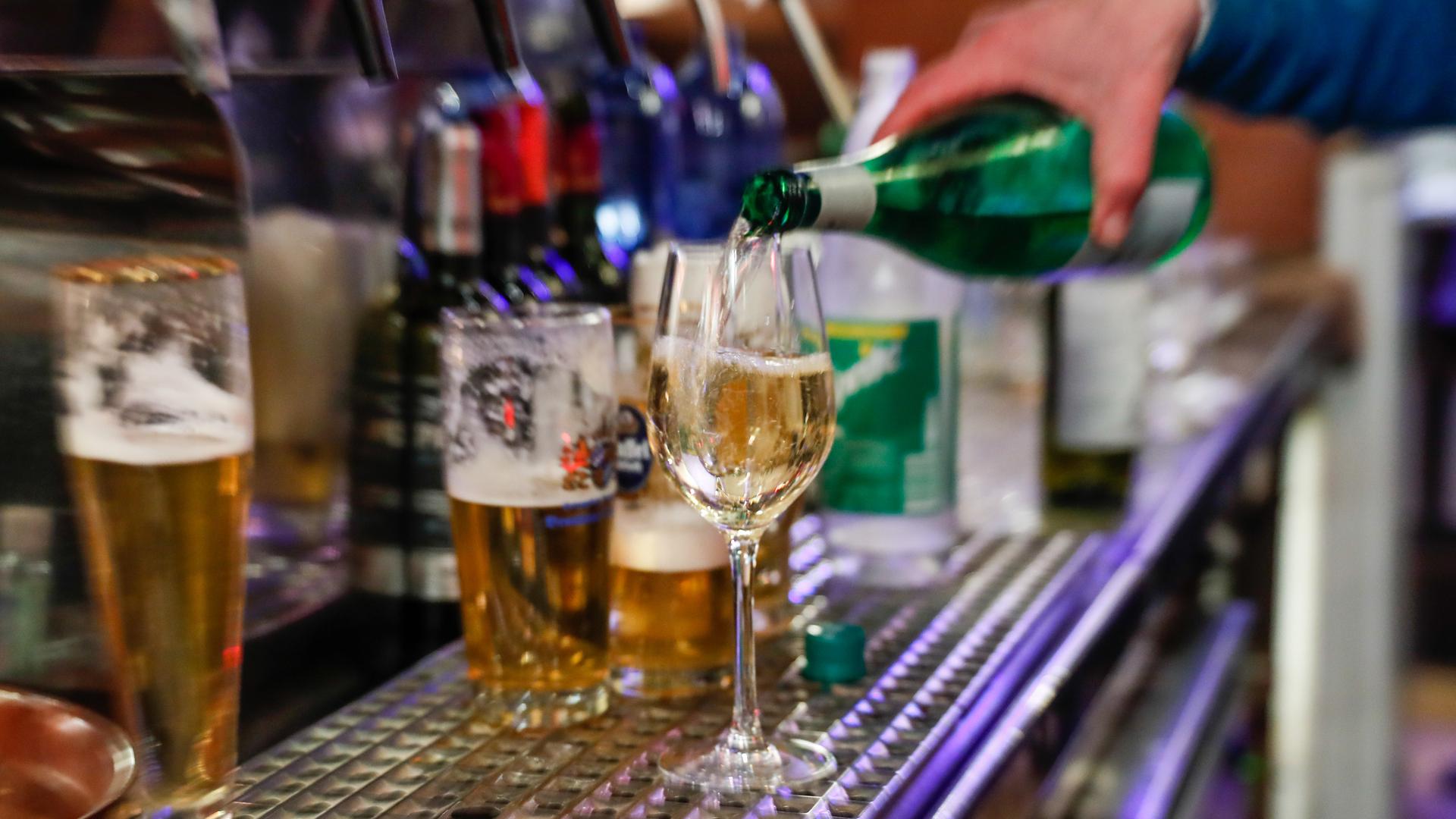 In einer Bar wird ein Glas Wein eingeschenkt.