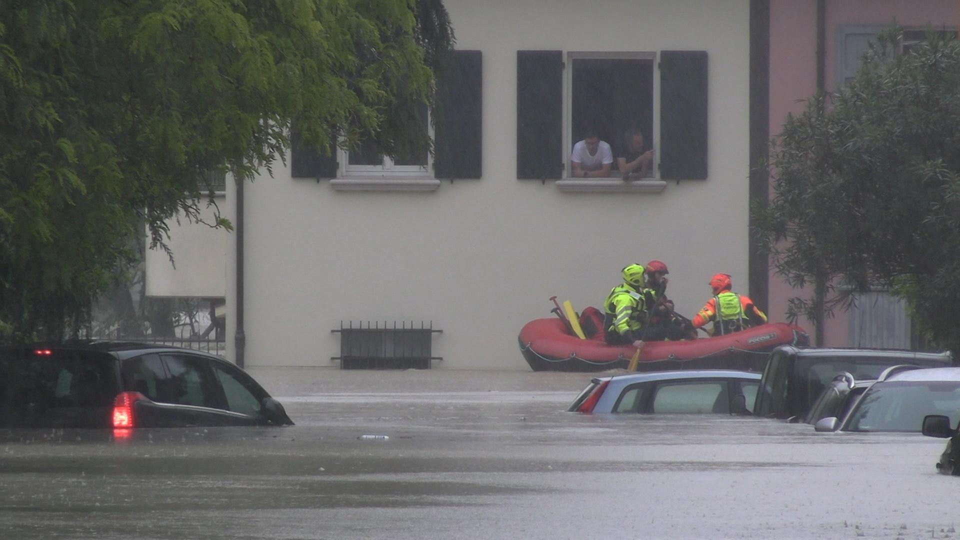 In der Stadt Cesena ist der Fluss Savio nach extremen Regenfällen über die Ufer getreten, Straßenzüge am Fluss stehen unter Wasser. Von Autos sieht man nur noch die Dächer, ein Schlauchboot mit Rettungskräften fährt an einem Haus vorbei, aus dem Menschen aus dem Fenster schauen.