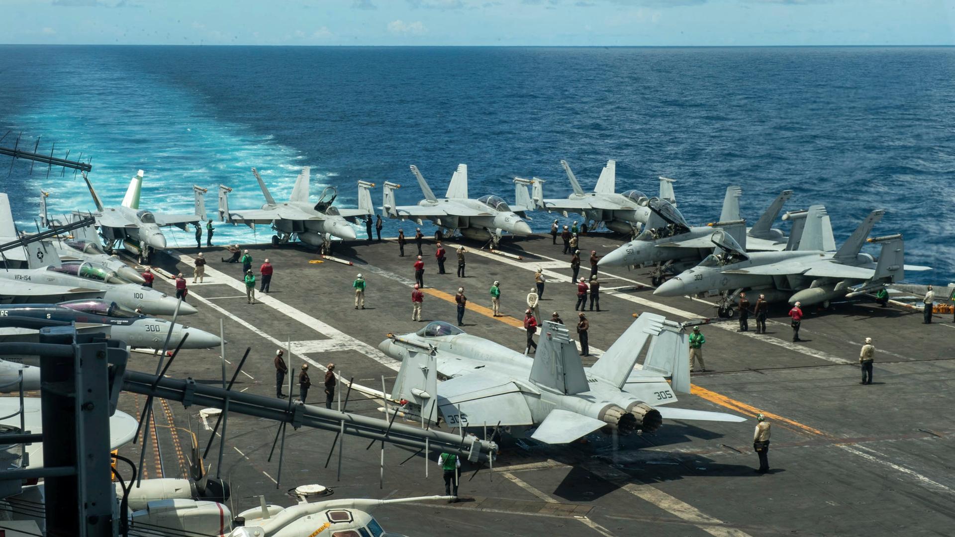 Das Flugdeck des Flugzeugträgers USS Theodore Roosevelt mit mehreren Kampfjets an Deck. 