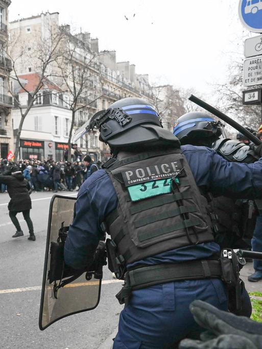 Ein französischer Polizist in Paris hebt einen Schlagstock