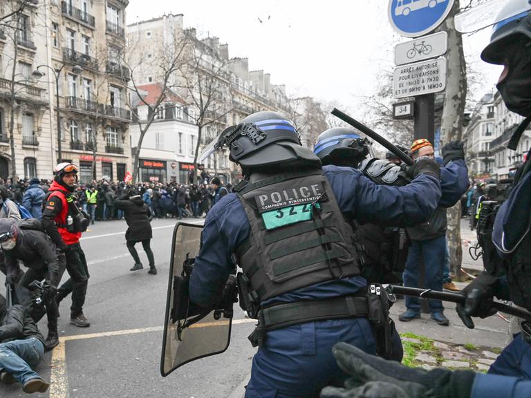 Ein französischer Polizist in Paris hebt einen Schlagstock