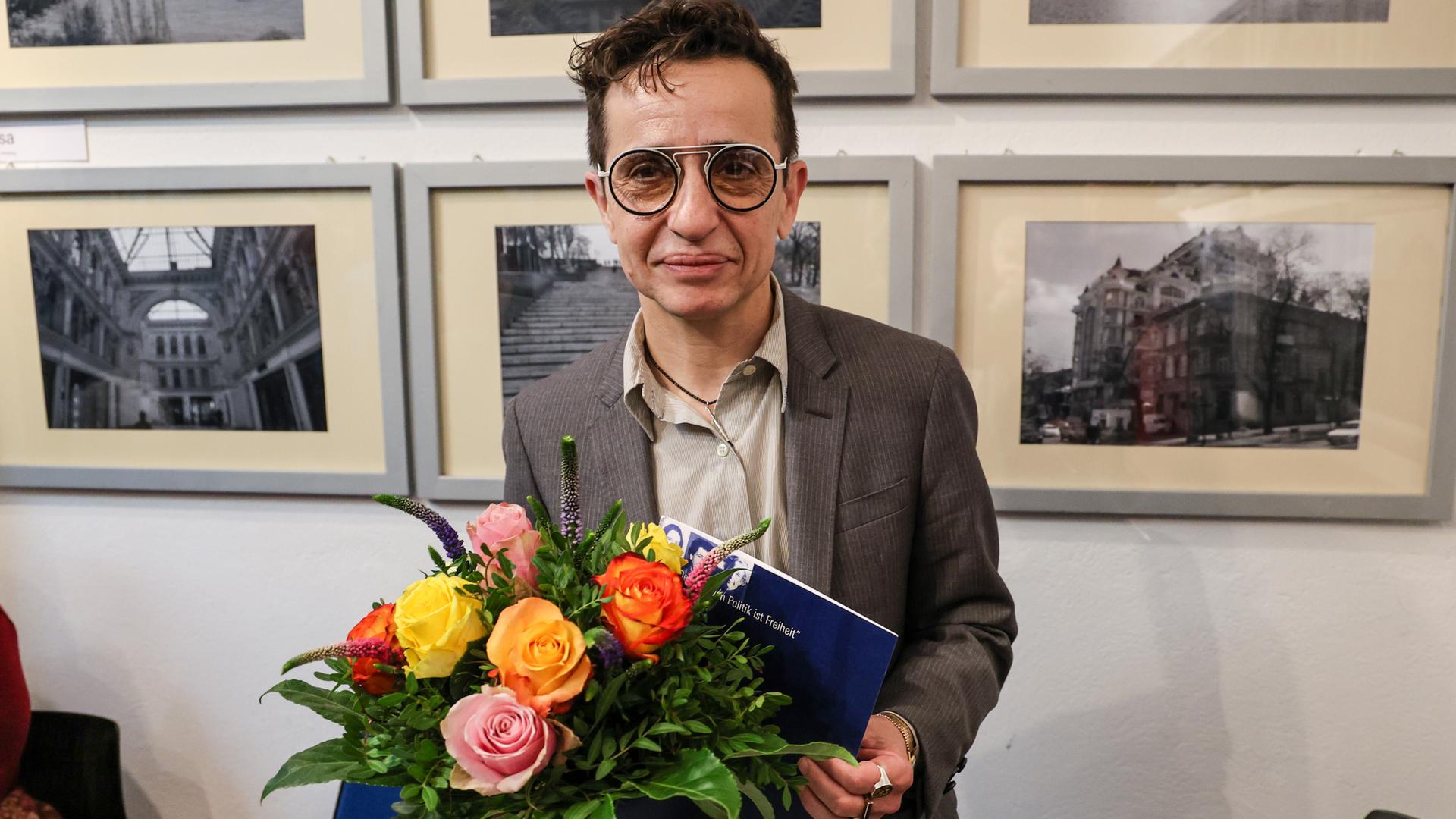 Masha Gessen, Publizistin aus den USA, steht nach der Übergabe des Hannah-Arendt-Preises im Veranstaltungsraum F61, und schaut in die Kamera. Gessen trägt eine Brille mit runden Gläsern, in der Hand hält sie einen Blumenstrauß.