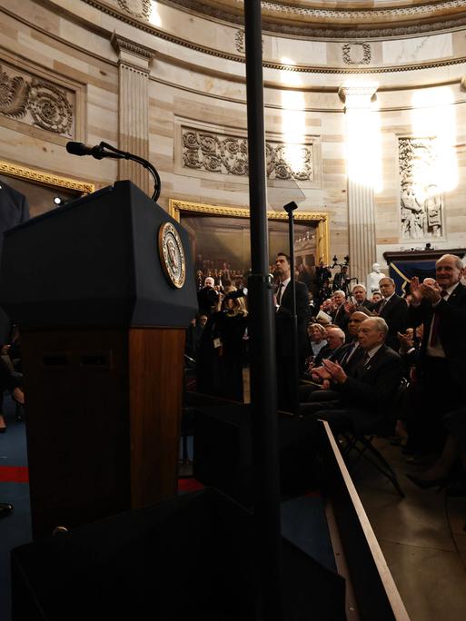 Donald Trump steht an einem Rednerpult im Kapitol und lächelt in die Kamera.