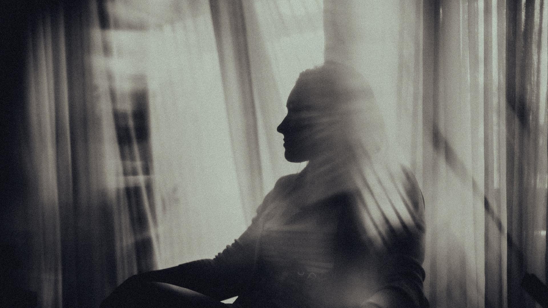 Die Konturen einer am Fenster sitzenden Frau