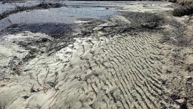 Trockenes Flussbett mit Spuren von Wellen auf dem Sand