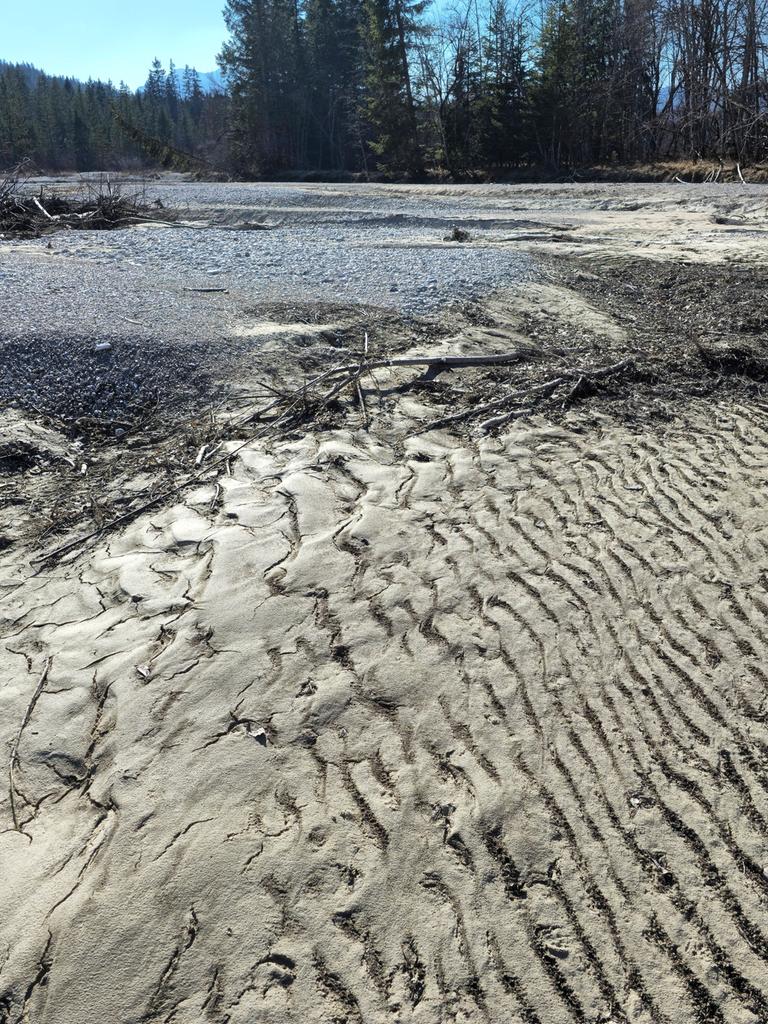 Trockenes Flussbett mit Spuren von Wellen auf dem Sand