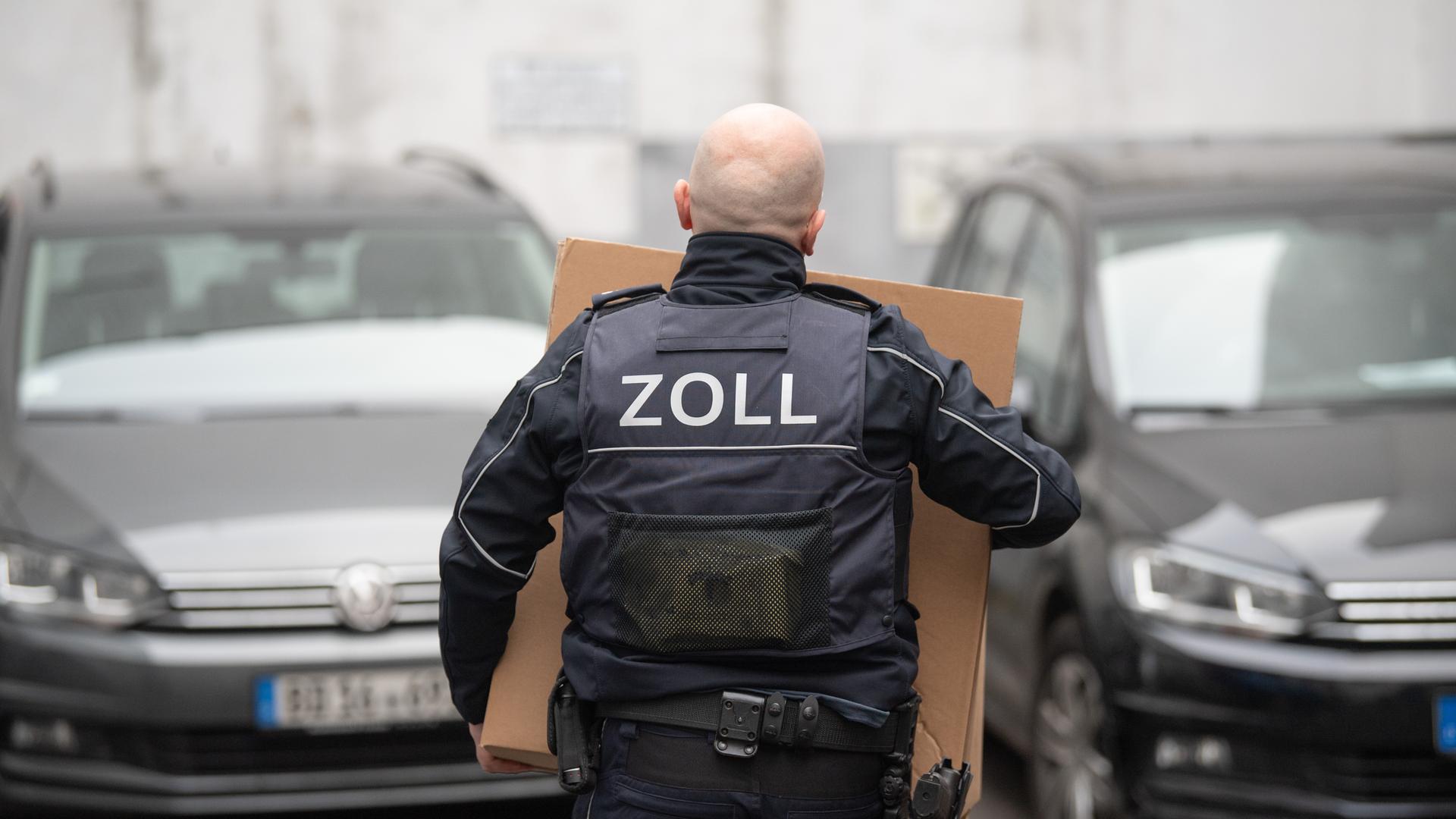 Zoll-Razzia gegen Schwarzarbeit: Kisten mit Beweismaterial tragen Beamte des Zoll bei einer Razzia.