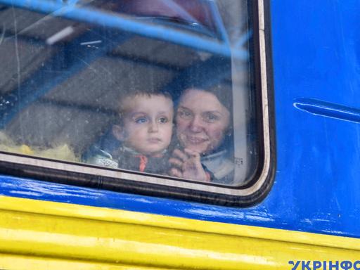 Eine Frau sitzt mit Kind in einem Evakuierungszug aus der Stadt Saporischschja.