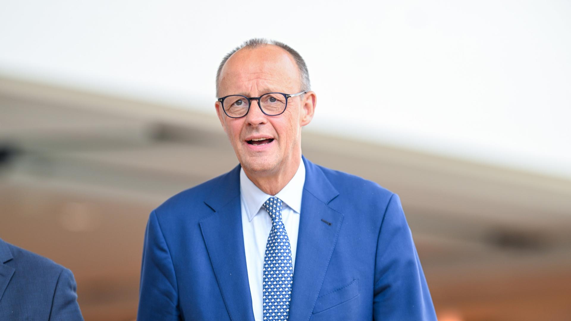 Bundeskanzler Friedrich Merz trägt einen blauen Anzug und läuft. Er besucht den Landesparteitag der CDU Niedersachsen am 23.08.2025 in Osnabrück.