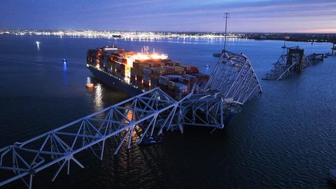 Ein Frachtschiff hat eine Brücke in den USA gerammt. Das Schiff liegt direkt an den Trümmern der Brücke.