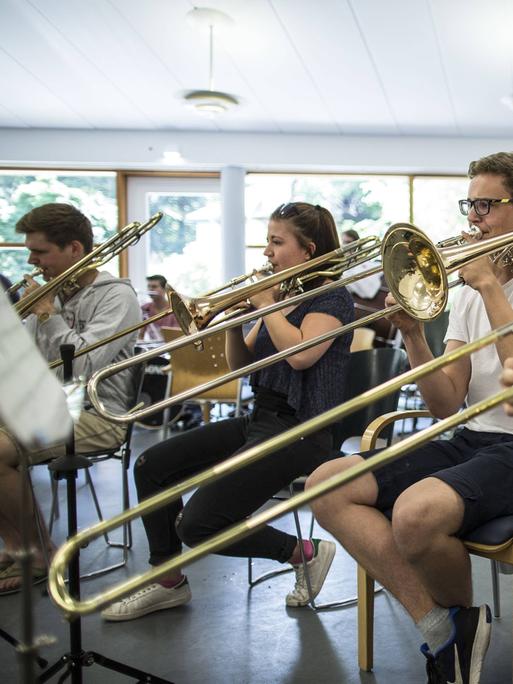 Eine Gruppe von Jungen und Mädchen bilden ein Bläser-Ensemble, das gerade konzentriert übt.