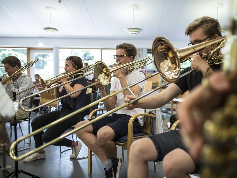 Eine Gruppe von Jungen und Mädchen bilden ein Bläser-Ensemble, das gerade konzentriert übt.