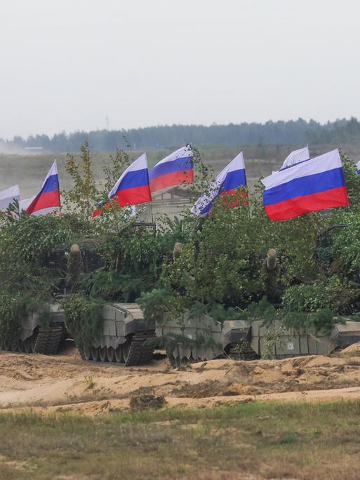 Mit grünen Pflanzen getarnte russische Panzer mit Fahnen bei der Militärübung Zapad 2025