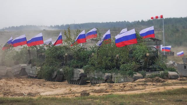 Mit grünen Pflanzen getarnte russische Panzer mit Fahnen bei der Militärübung Zapad 2025