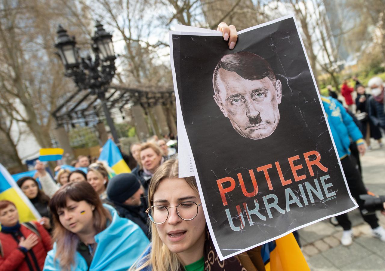 April 2022: Plakat mit einem Kopf, der eine Mischung aus Hitler und Putin darstellen soll, bei einer Demonstration in Frankfurt am Main gegen den Krieg in der Ukraine