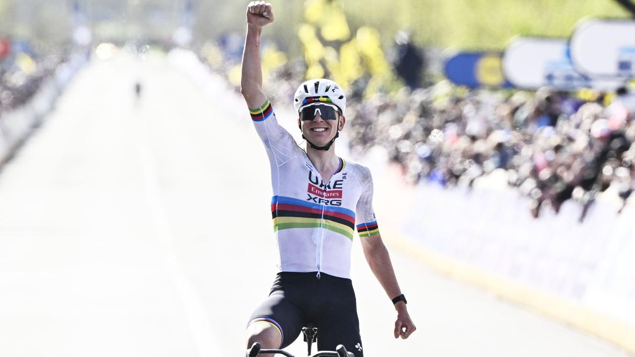 Tadej Pogacar jubelt bei der Zieleinfahrt über seinen Sieg und reckt dabei den rechten Arm mit einer Faust hoch.