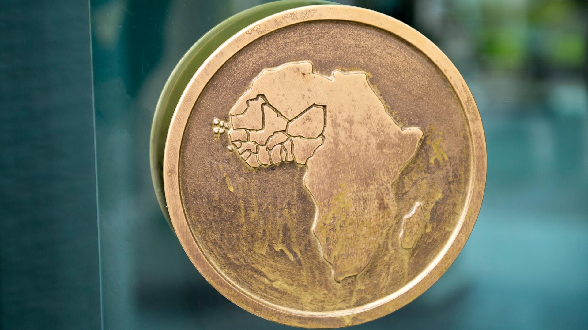 Auf einem bronzefarbenen Knauf an einer Glastür ist der Umriss des Kontinents Afrika abgebildet.
