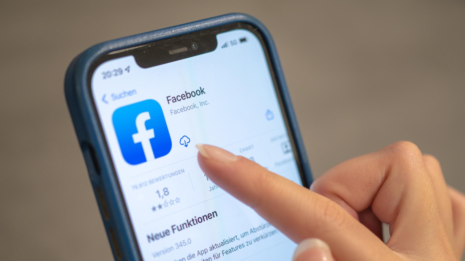 Eine Frau hält ihr Handy in der Hand, auf dem die Facebook-App zu sehen ist. Eine Frau hält ihr Handy in der Hand, auf dem die Facebook-App zu sehen ist.