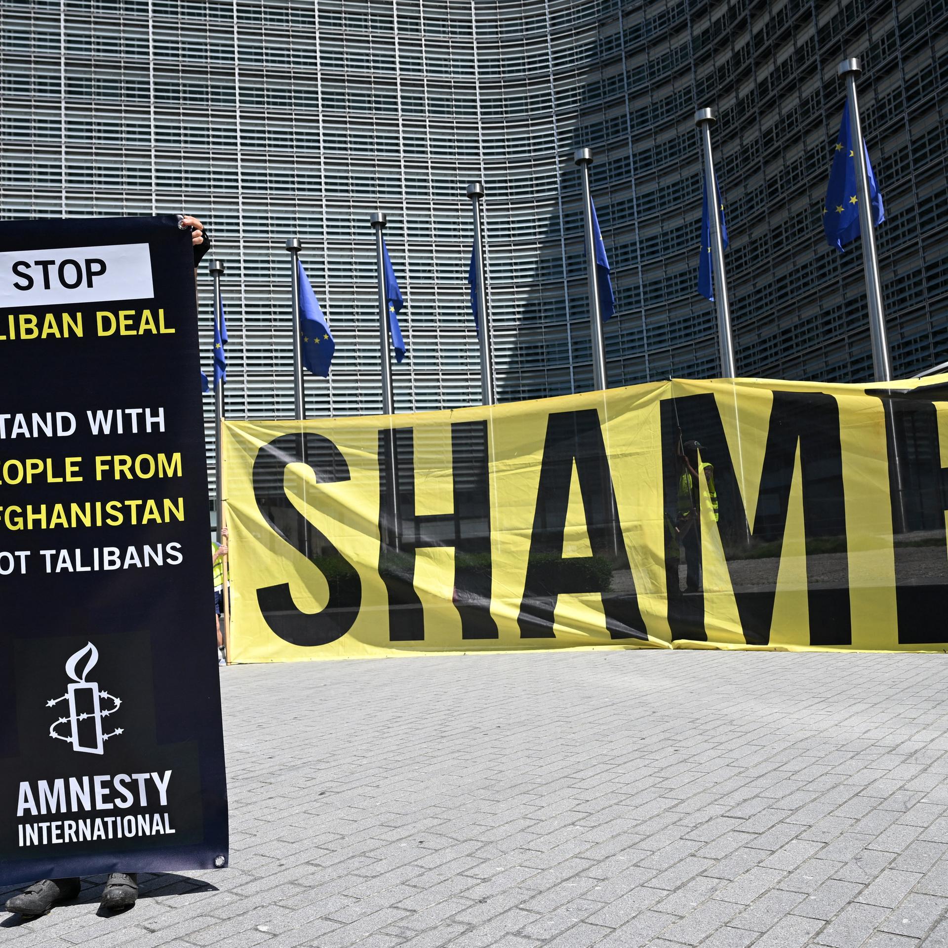 Eine Aktivistin von Amnesty International protestiert am 23. Juni 2026 vor dem Hauptsitz der EU-Kommission in Brüssel mit einem Transparent gegen ein Treffen mit einer Taliban-Delegation. 