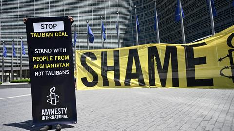 Eine Aktivistin von Amnesty International protestiert vor dem Hauptsitz der EU-Kommission in Brüssel mit einem Transparent gegen ein Treffen mit einer Taliban-Delegation. 