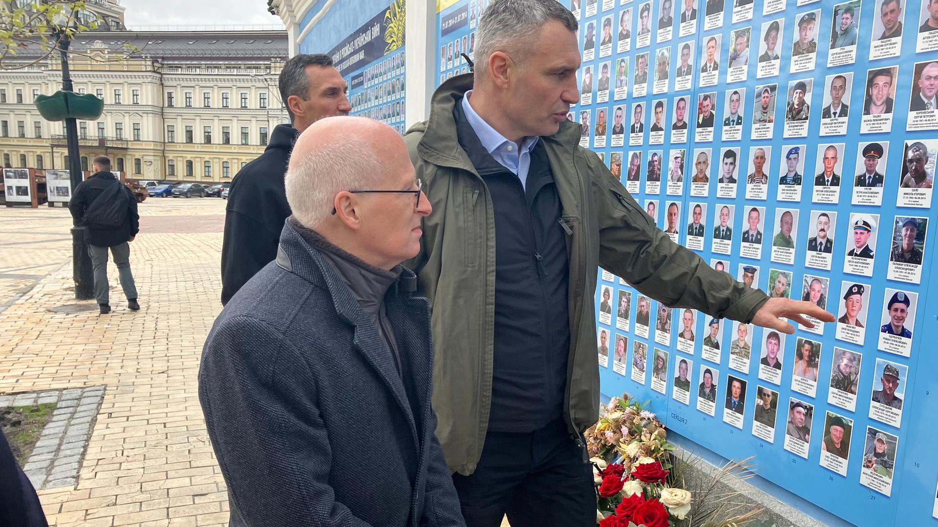 Peter Tschentscher, Erster Bürgermeister von Hamburg, und Kiews Bürgermeister Vitali Klitschko betrachten Gedenktafeln für im Krieg mit Russland gefallene ukrainische Soldaten an der Außenmauer des St. Michaelsklosters in Kiew.