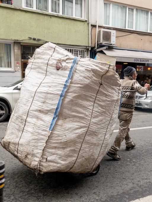 Ein Mann fährt mit einem Karren mit einem großen weißen Sack durch die Straße in Istanbul und sammelt Wertstoffe von Haushalten und Unternehmen,Türkei 2023.