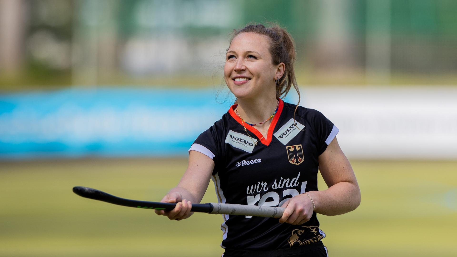 Nike Lorenz, deutsche Hockeyspielerin, im Trikot mit Schläger in der Hand, lächelt.