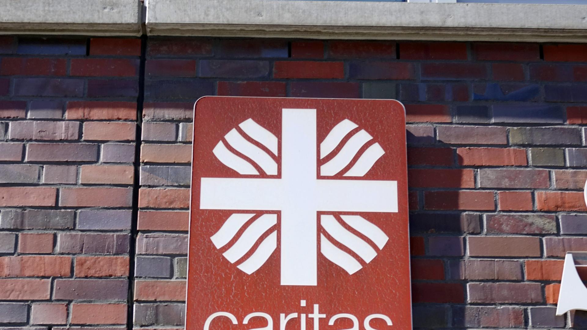 Das Logo der Caritas, des Deutschen Caritasverbandes, hängt an einer Hauswand. Die Caritas ist ein Wohlfahrtsverband der römisch-katholischen Kirche in Deutschland. Er ist als eingetragener Verein organisiert.