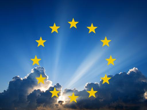 Wolken am Himmel, durch die Sonne scheint. Darauf eine Grafik der 12 gelben Sterne der europäischen Flagge. 