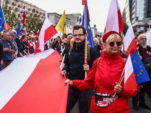 Menschen halten bei der Demo "Marsch der Millionen Herzen" Polen- und EU-Flaggen hoch.