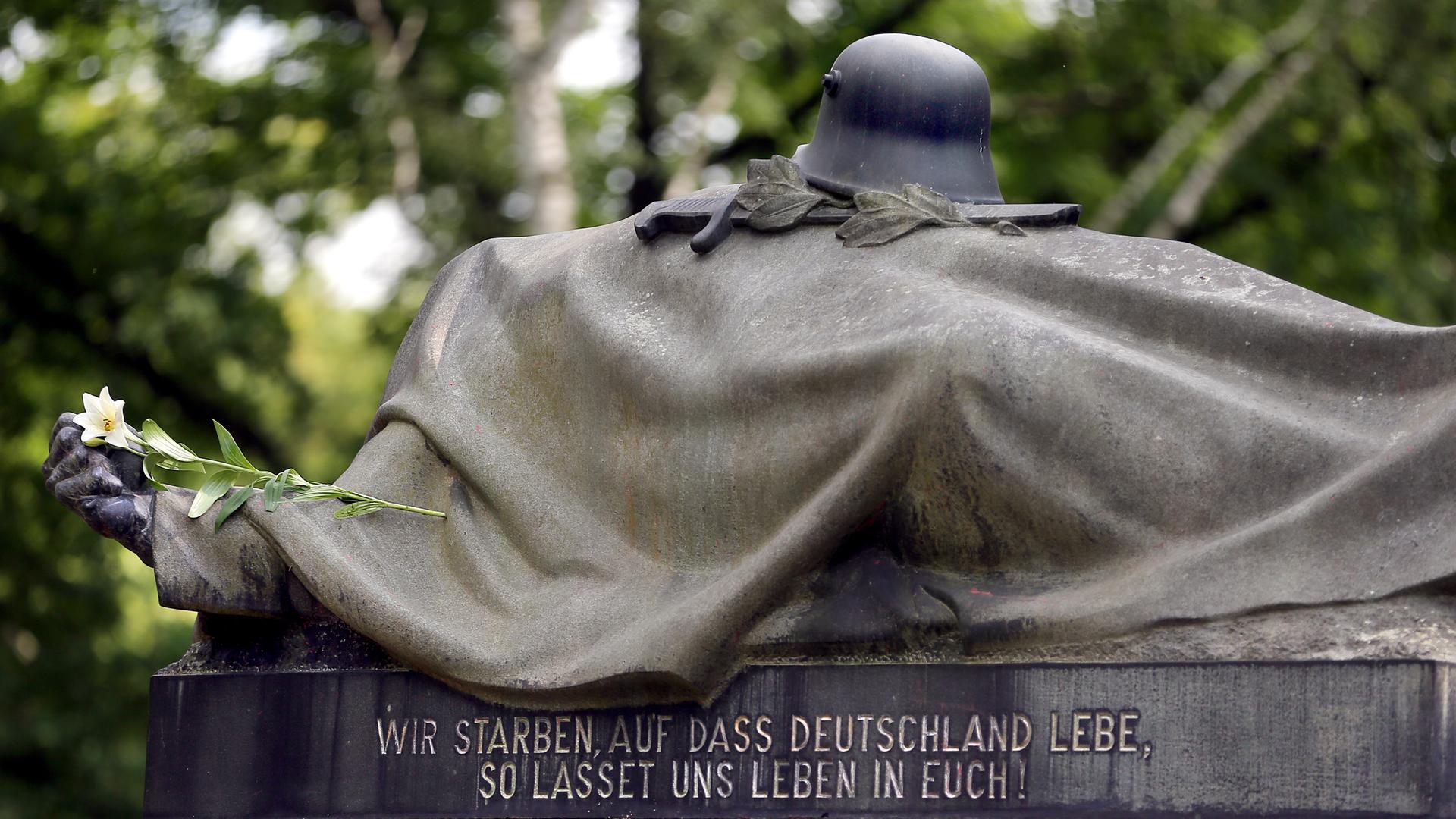 Eine weiße Lilie liegt auf einem Kriegerdenkmal des Garnisonsfriedhofes in Berlin und erinnert an die gefallenen Soldaten des Ersten Weltkriegs. 