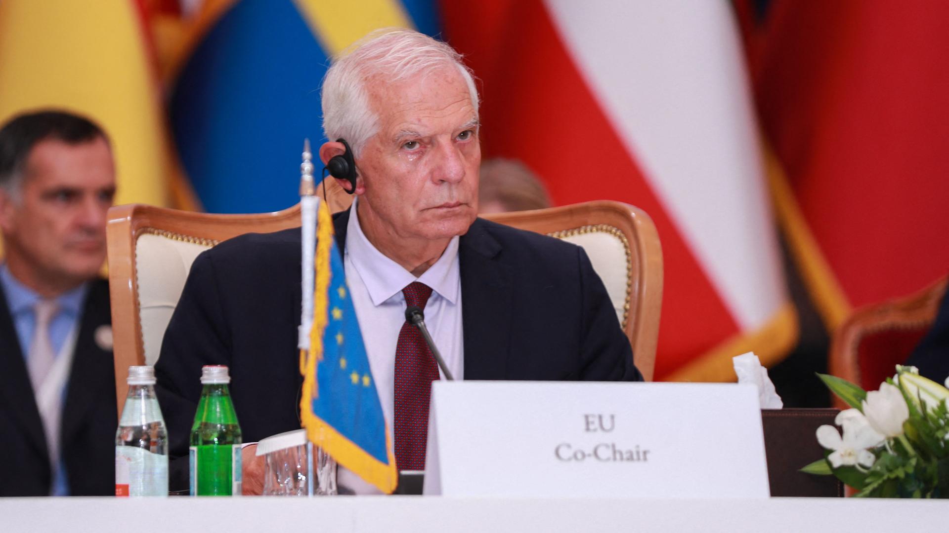 Der EU-Außenbeauftragte Borrell sitzt mit einem Mikrofon im Ohr hinter einem Pult, vor ihm die EU-Fahne.